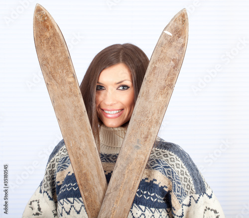 Photo: young woman in sweater holding old wooden ski young woman in sweater holding old wooden ski