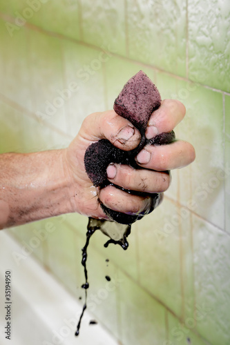 Photo: Human hand squeezing dirty sponge after cleaning Human hand squeezing dirty sponge after cleaning