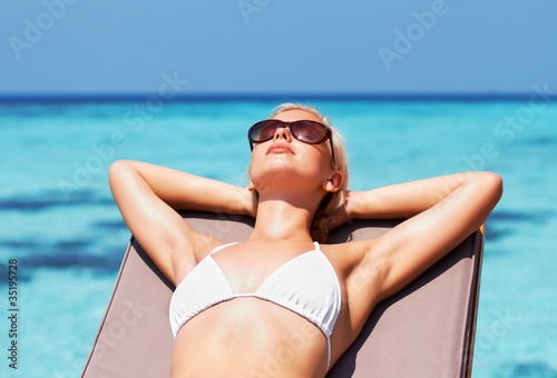 Foto: Young pretty girl sunbathing by the seaside Young pretty girl sunbathing by the seaside