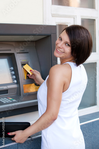 Photo: Woman withdrawing money from credit card at ATM Woman withdrawing money from credit card at ATM