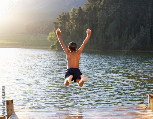 Photo: Young boy jumping into lake Young boy jumping into lake
