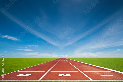 Photo: Running track with three lanes over sky and clouds Running track with three lanes over sky and clouds