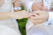 Groom putting a wedding ring on bride's finger