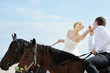 Beach wedding: bride and groom on a horses by the sea
