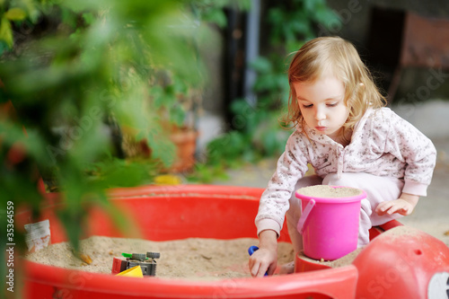 Photo: Adorable little girl playing in a sandbox Adorable little girl playing in a sandbox