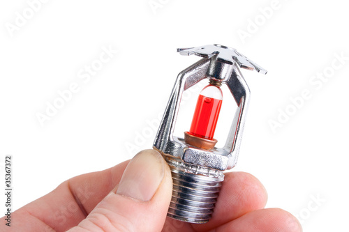 Photo: Fire sprinkler head in hand, isolated on white Fire sprinkler head in hand, isolated on white