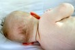 bébé nu de dos allongé sur le coté
