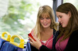 Two teenage girls sitting on a bus, listening to music