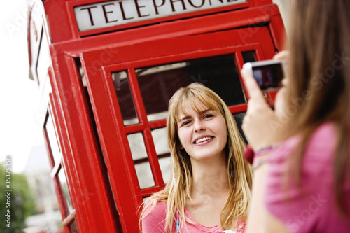 Foto: Two teenagers taking photographs in front of a telephone box Two teenagers taking photographs in front of a telephone box