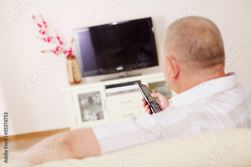 Photo: Televiewer on sofa with TV remote control Televiewer on sofa with TV remote control