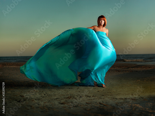 Foto: woman on beach wind blowing blue dress woman on beach wind blowing blue dress