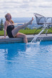 Laughing woman on swimming pool edge splashing