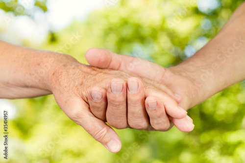 Photo: Closeup of old people hands holding together outdoor Closeup of old people hands holding together outdoor