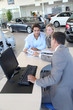 Car seller and couple looking at catalogue