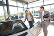 Car seller with couple in car dealership