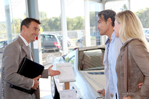 Photo: Car seller with couple in car dealership Car seller with couple in car dealership