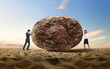Businessman rolling a giant stone
