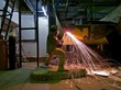 A workman flame cutting a lage metal tank