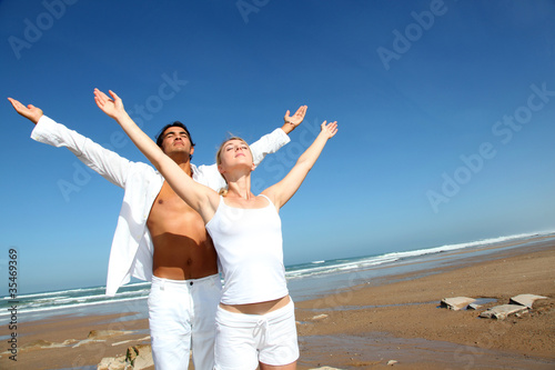 Foto: Couple doing yoga exercises on the beach Couple doing yoga exercises on the beach