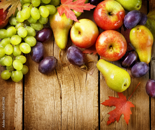 Photo: Organic Fruits over wood background. Autumn harvest Organic Fruits over wood background. Autumn harvest