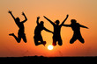silhouette of friends jumping in sunset