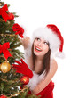 Girl in santa hat by christmas tree. Girl in santa hat by christmas tree.