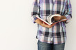 Foto: Young man against the wall reading a book Young man against the wall reading a book