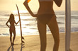 Women Surfers In Bikinis With Surfboards At Sunset Beach