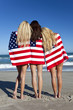 Three Young Women Wrapped in American Flags on a Beach