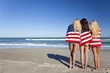Three Young Women Wrapped in American Flags on a Beach