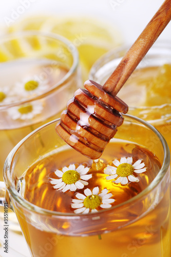 Photo: cup of herbal tea with chamomile flowers and wooden stick honey cup of herbal tea with chamomile flowers and wooden stick honey