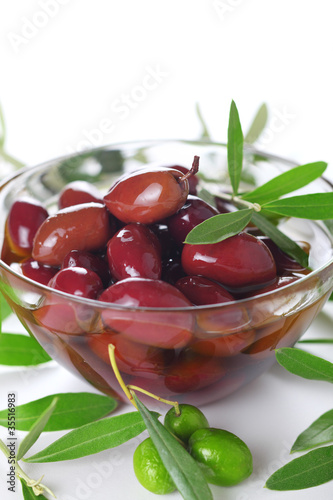 Photo: Black olives in oil closeup on white isolated background Black olives in oil closeup on white isolated background