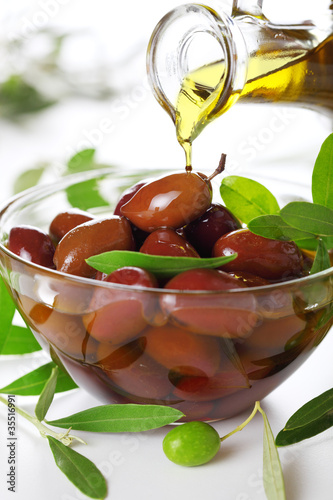 Photo: Olive oil poured from an original bottle into black olive Olive oil poured from an original bottle into black olive