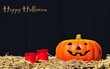 Calabaza con dos velas y Feliz Halloween.