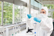 Protected female scientist pouring liquid in a Erlenmeyer flask