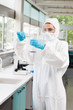 Portrait of a protected female scientist pouring liquid in a Erl