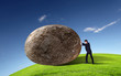Businessman rolling a giant stone