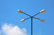 Light pole with four lights against blue sky and cloud