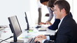 Business man working on computer with colleagues