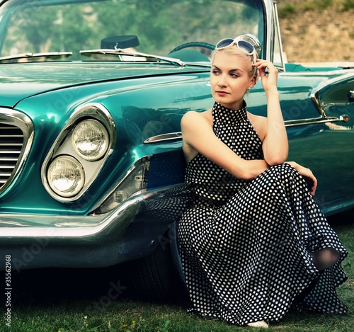 Photo: Beautiful lady sitting near retro convertible. Beautiful lady sitting near retro convertible.