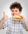 Boy eating big sandwich showing OK sign