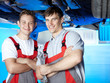 Two motor mechanics checking a car on service lift