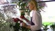 Girl at work in flowers shop and smelling red roses