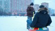 Young boy starts pulling sled with other boy