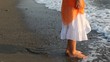 Woman in white douses barefoot feet in waves
