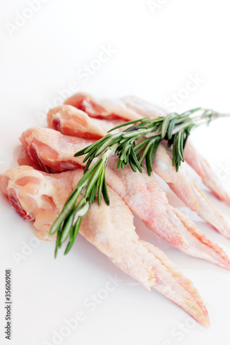 Photo: raw chicken wings with rosemary on white background raw chicken wings with rosemary on white background