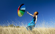 Redhead girl with umbrella at windy grass meadow.