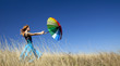 Redhead girl with umbrella at windy grass meadow.