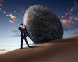 Businessman rolling a giant stone