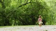 Girl runs away across forest meadow all strewn fluff